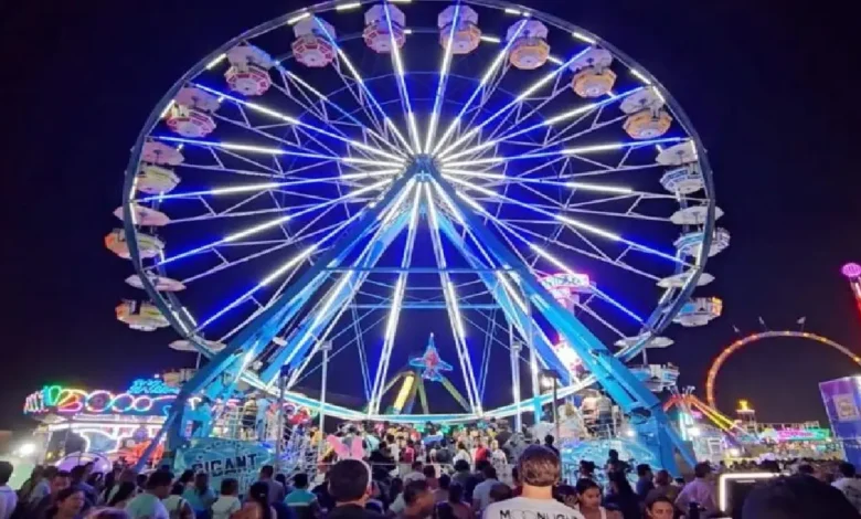 Gran rueda de la fortuna iluminada durante la noche en la Feria Tabasco, con una multitud de asistentes disfrutando del ambiente festivo.